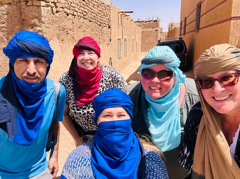 Travelers wearing colorful Amazigh turbans exploring a Moroccan medina